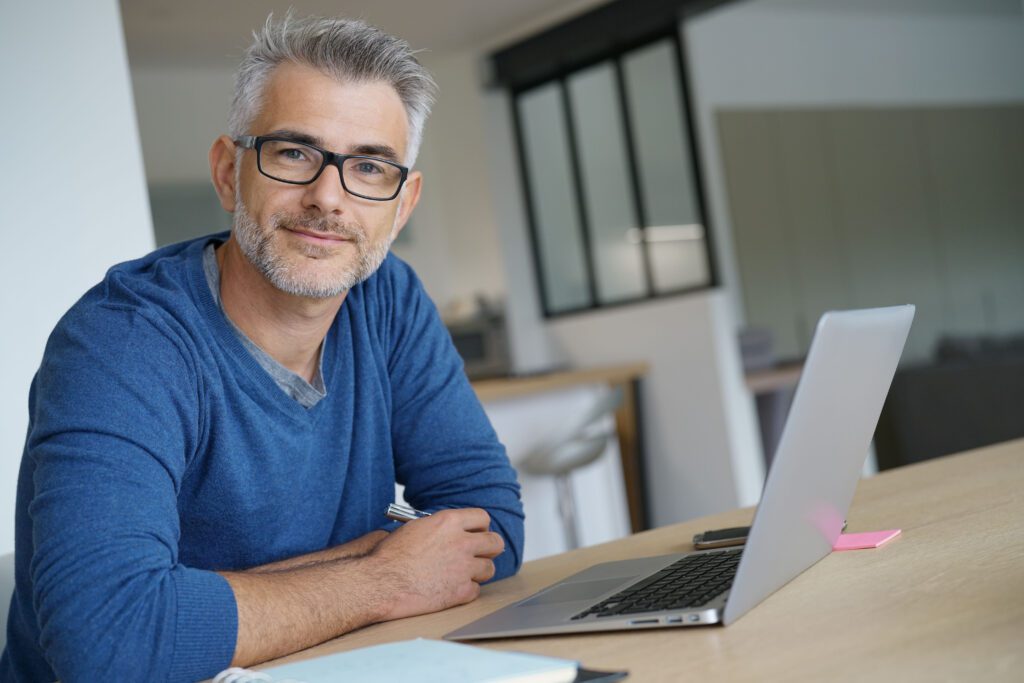Smiling man with glasses at laptop