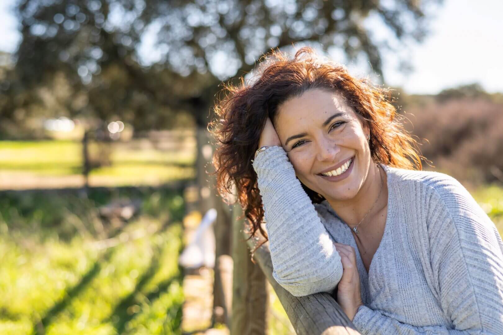 A woman smiling and holding her head in the air.